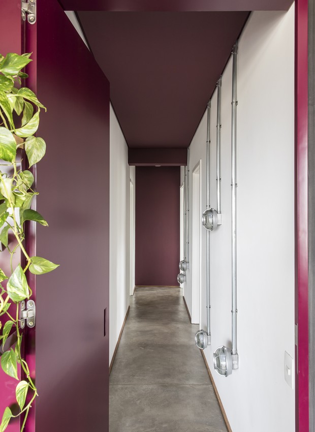 CORREDOR | Concreto no piso, iluminação em conduítes e do roxo berinjela no teto e portas de corredor de apartamento. Projeto do Superlimão (Foto: Maira Acayaba/Divulgação)