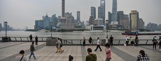 Pessoas passeiam ao longo do rio Huangpu, em Xangai, após a flexibilização das restrições da Covid-19 na cidade.  — Foto: Hector RETAMAL / AFP