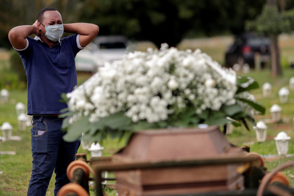 Gerson James, de 34 anos, chora durante o enterro do pai, Frank James Santana, de 54, que morreu de Covid-19 — Foto: Ueslei Marcelino/Reuters