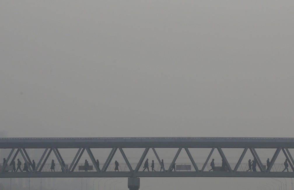 Pessoas caminham em uma ponte para pedestres em Pequim, na China. â Foto: Jason Lee/Reuters