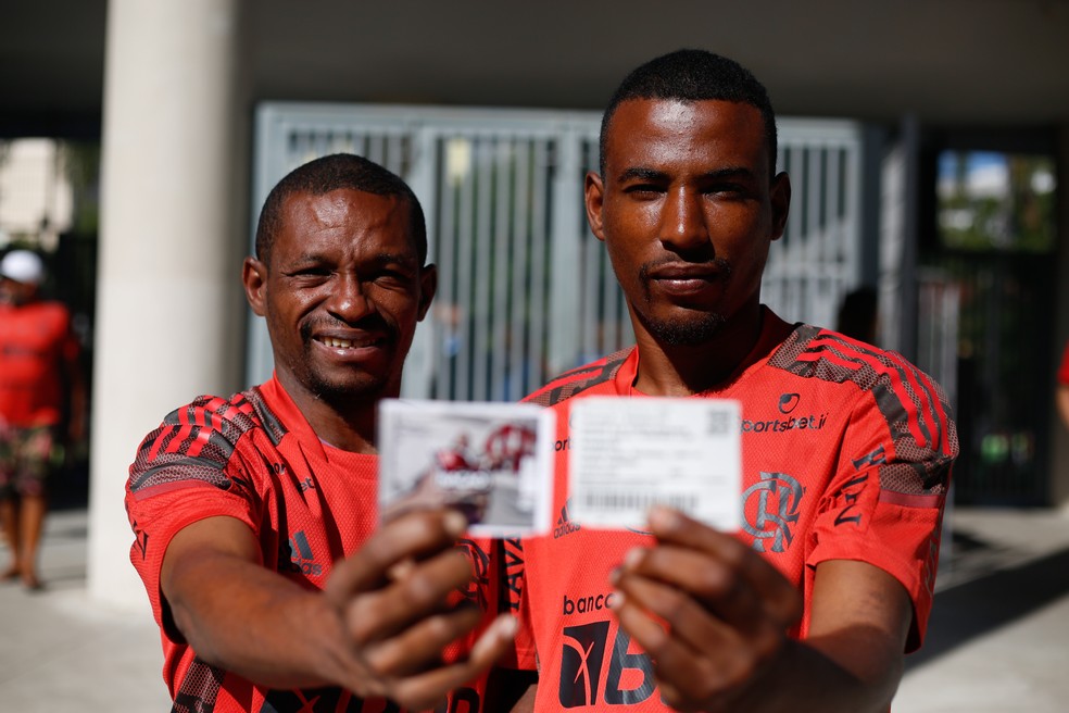 Torcedores em situação de rua exibem seus ingressos de Flamengo x Athletico-PR — Foto: Gilvan de Souza/Flamengo