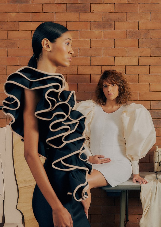 Fotografadas no ateliê da marca, no Rio, Monique (sentada) usa vestido de linho e tafetá e Ivy Ferreira usa vestido de lycra, ambos da coleção verão 2022 da Argalji (Foto: Bruna Sussekind)