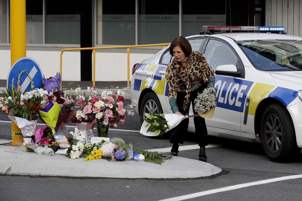 Mulher deposita buquê de flores em homenagem a mortos em atentado a mesquita em Christchurch, Nova Zelândia — Foto: Mark Baker/AP Photo