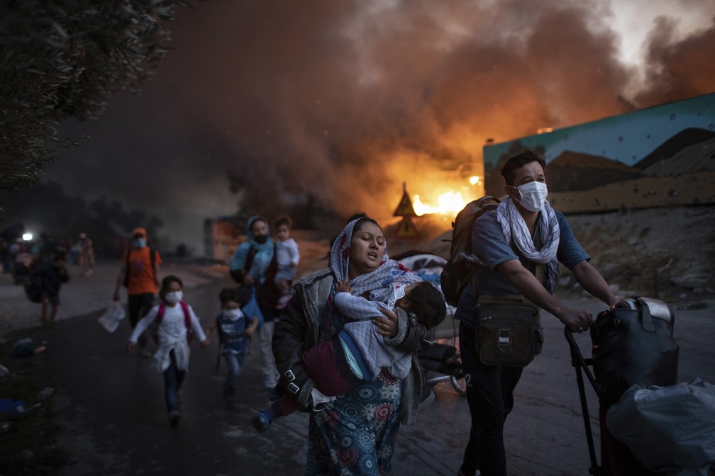 9 de setembro - Migrantes fogem do segundo incêndio em dois dias no campo de refugiados de Moria, na ilha de Lesbos, na Grécia — Foto: Petros Giannakouris/AP