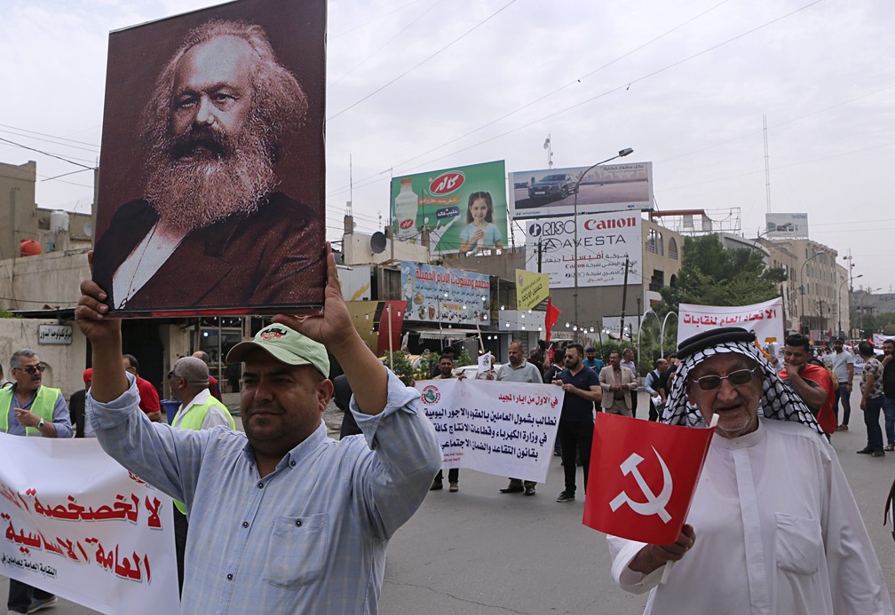 Em Bagdá, no Iraque, um homem segura uma foto de Karl Marx durante uma manifestação do partido comunista iraquiano nesta quarta (1º).  — Foto: Khalid Mohammed/AP