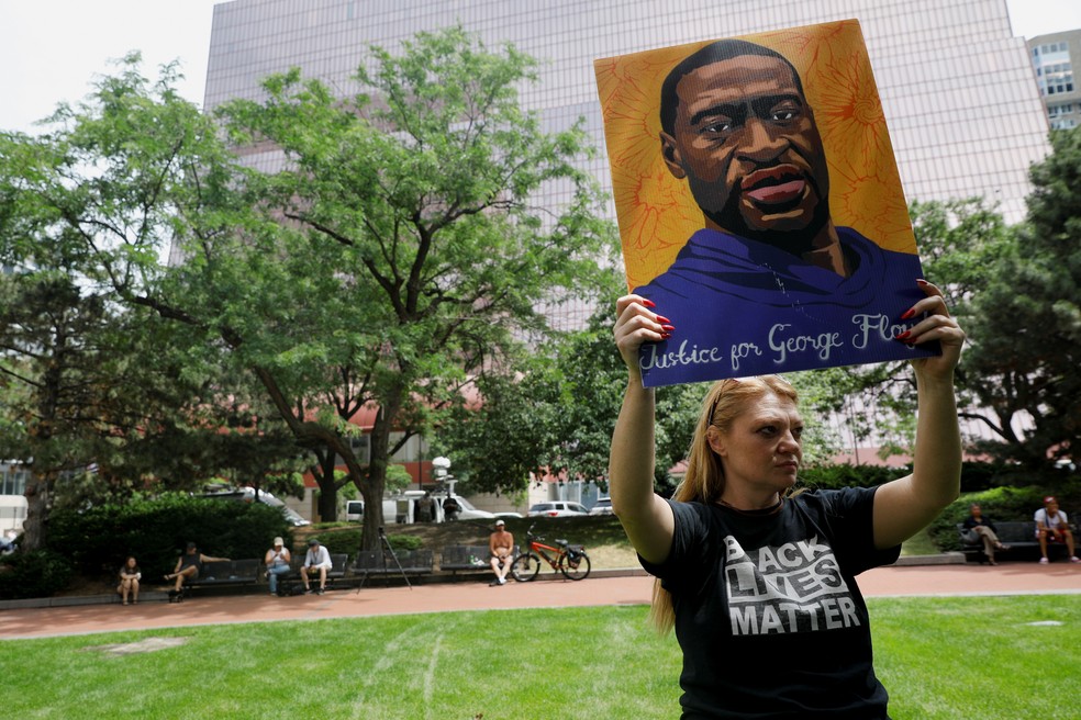Mulher ergue cartaz com retrato do ex-segurança George Floyd em Mineápolis, EUA, em 25 de abril de 2021 — Foto: Nicholas Pfosi/Reuters
