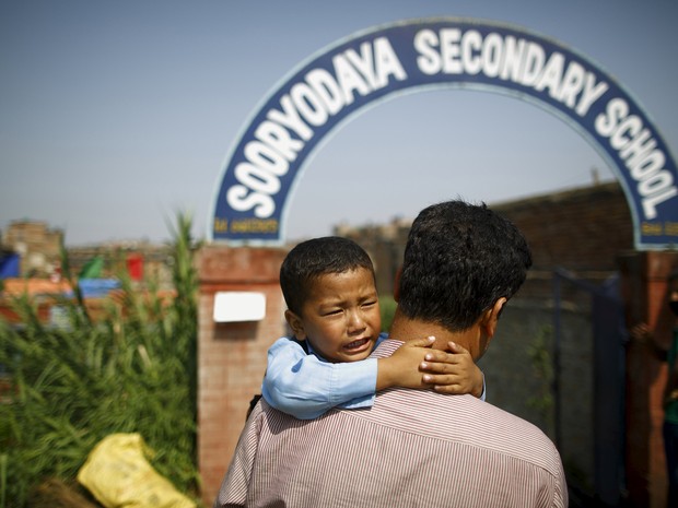 Saksham Karmacharya, de 4 anos, chora nos braços do pai e pede para não ir para escola (Foto: Reuters/Navesh Chitrakar)