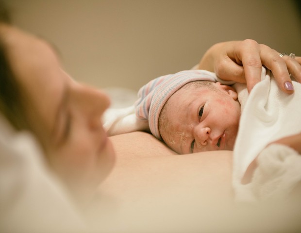 Mãe com recém-nascido no colo depois de parto normal hospitalar (Foto: Getty Images)