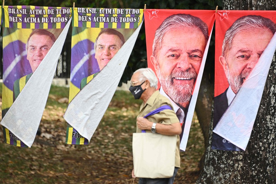 Pedestre passa por toalhas com estampas de Bolsonaro e Lula vendidas em via de Brasília