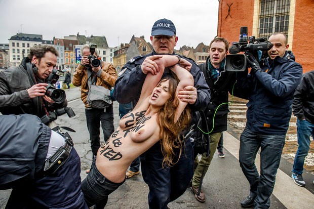 Ativista do Femen é arrastada por policial após se jogar sobre o carro de Dominique Strauss-Kahn, na chegada do ex-diretor do FMI ao seu julgamento em Lille nesta terça-feira (10) (Foto: Philippe Huguen/AFP)