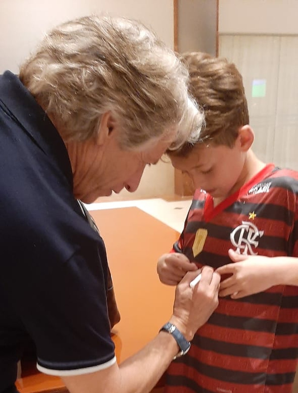 Jorge Jesus assinando uma camisa do Flamengo no hotel — Foto: Rodrigo Cerqueira / GloboEsporte.com