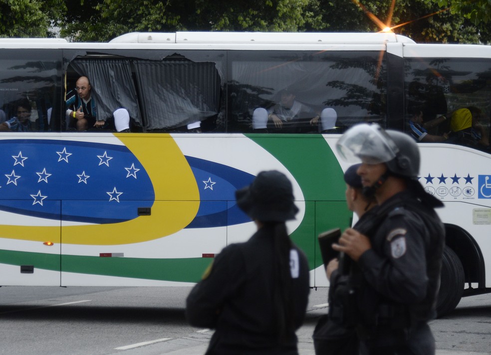 Janela de &ocirc;nibus quebrada com PMs observando a chegada dos visitantes &mdash; Foto: Andr&eacute; Dur&atilde;o