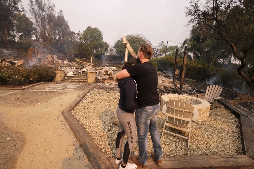 Casal se abraça ao ver casa destruída por incêndio em Malibu, no sul da Califórnia — Foto: Ringo H.W. Chiu/AP Photo