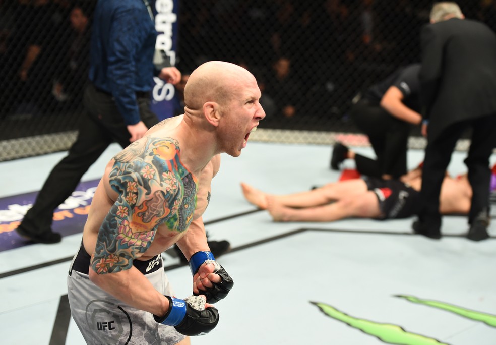 Com Ricardo Lamas apagado ao fundo, Josh Emmett comemora sua vitória em Winnipeg (Foto: Josh Hedges/Getty Images)