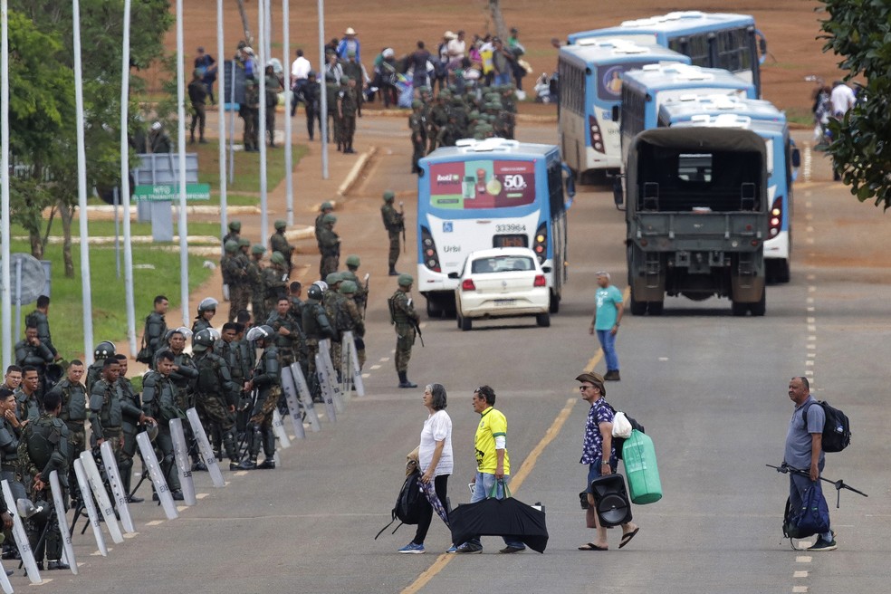 Polícia acompanha enquanto bolsonaristas deixam o acampamento golpista diante do QG do Exército em Brasília — Foto: Gustavo Moreno/AP