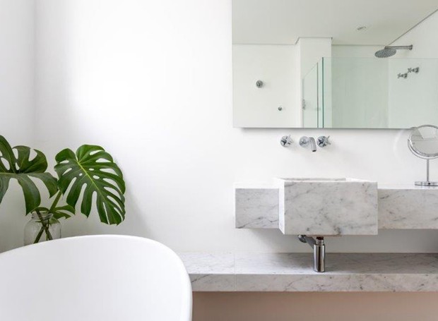 BANHEIRO | Projetado pelo escritório CR2 Arquitetura, o banheiro todo branco tem pia e prateleira de Marmoglass. Espelho cristal incolor executado por Esquema Vidros (Foto: Fran Parente/Divulgação)