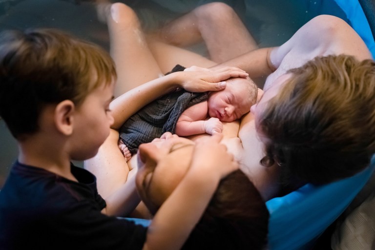  Esta imagem comovente, também capturada por Renate Van Lith, mostra um menino fazendo carinho na cabeça da mãe enquanto ela embala o recém-nascido (Foto: Renate Van Lith)