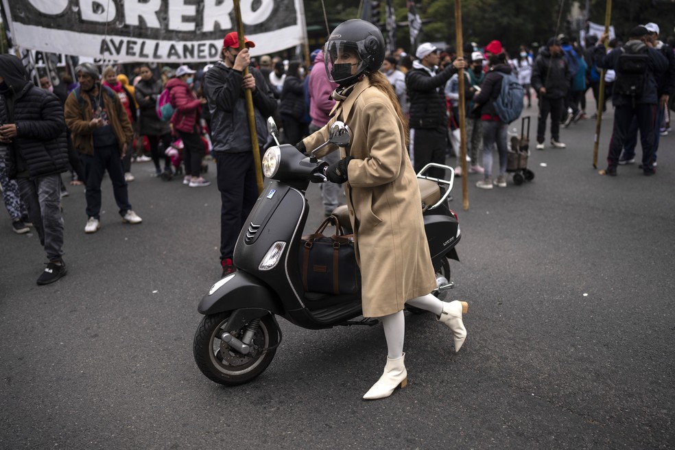 Mulher empurra sua motocicleta durante protestos na Argentina — Foto: Rodrigo Abd/AP