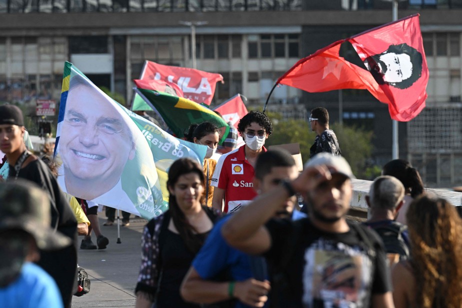 Apoiadores de Bolsonaro e de Lula exibem bandeiras com homenagens aos candidatos em parada de ônibus em Brasília