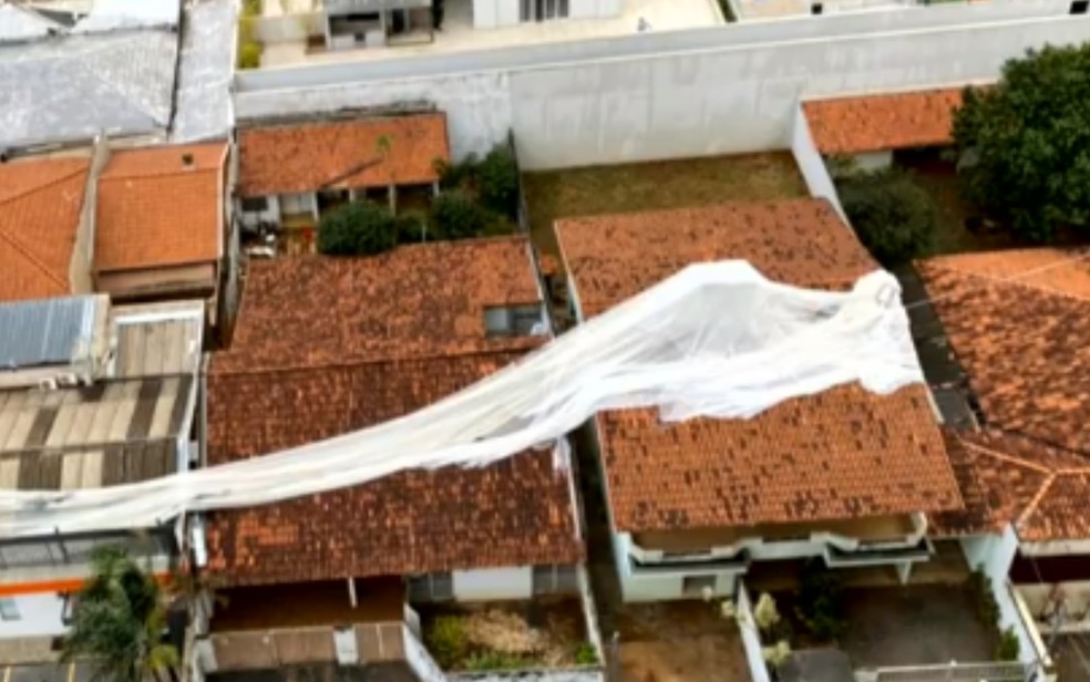 Lona de prédio 'voa' para telhado de casas após forte ventania, em Goiânia  — Foto: Reprodução/TV Anhanguera