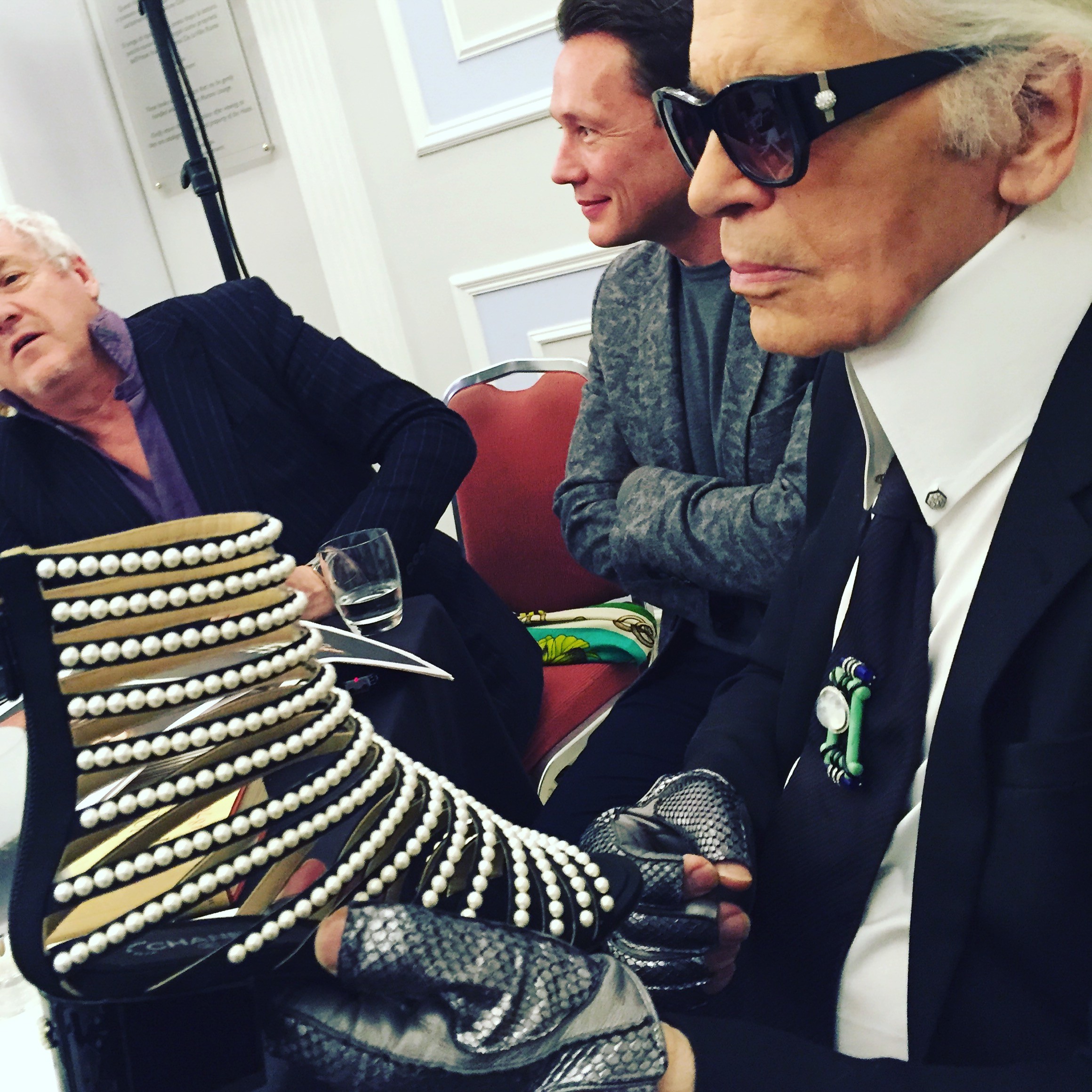 In Karl’s gloved hand a pearl of a shoe with ribs of pearls on a sandal boot (Foto: SuzyMenkesVogue)