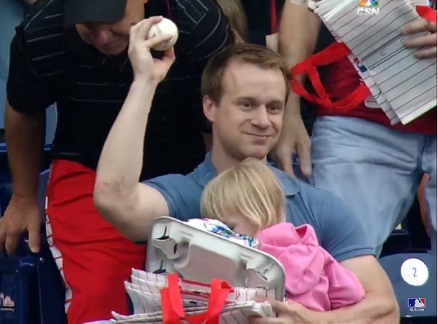 Pai segura bola de beisebol com uma mão e carrega filha com a outra (Foto: Reprodução Youtube)