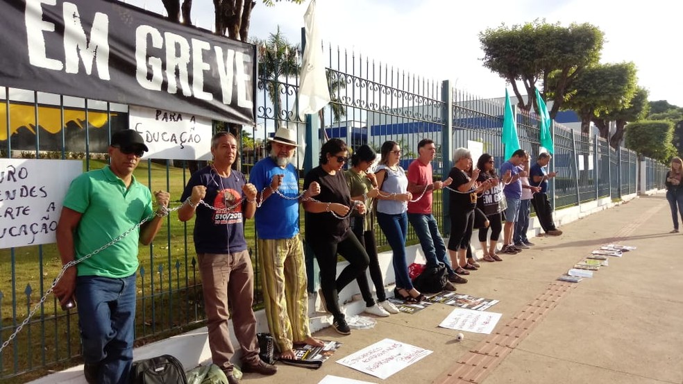 Servidores da Educação em greve se acorrentam em protesto na frente da sede do governo em Cuiabá — Foto: Sintep-MT/Divulgação