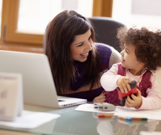 Mulher trabalhando com criança do lado (Foto: Shutterstock)