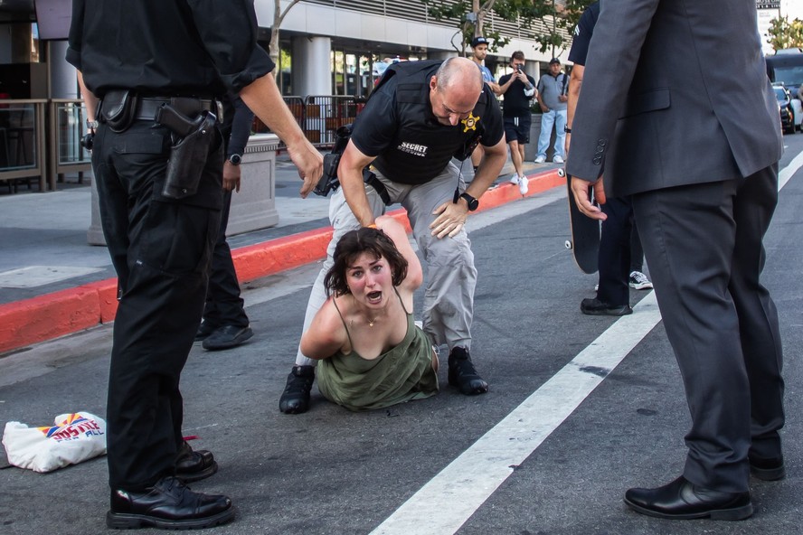 Policial do Serviço Secreto americano imobiliza manifestante no chão depois que ela correu em direção a uma carreata a caminho do Centro de Convenções de Los Angeles, onde os líderes norte e sul-americanos estão reunidos para a nona Cúpula das Américas em Los Angeles, em 8 de junho de 2022