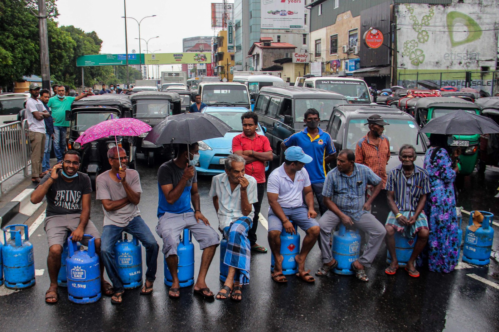 Pessoas sentadas em cilindros de gás vazios  bloqueiam estrada para protestar contra a escassez de combustível e gás de cozinha em Colombo, no Sri LankaAFP