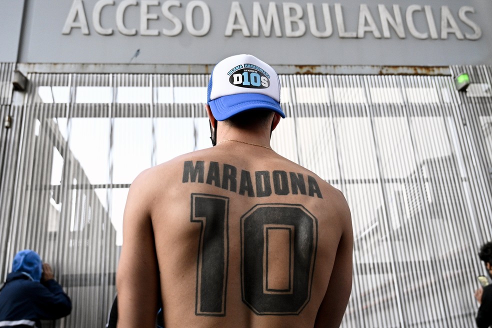 Fã com grande tatuagem com o nome de Maradona faz plantão em hospital onde ídolo passou por cirurgia — Foto: Juan Mabromaga/AFP
