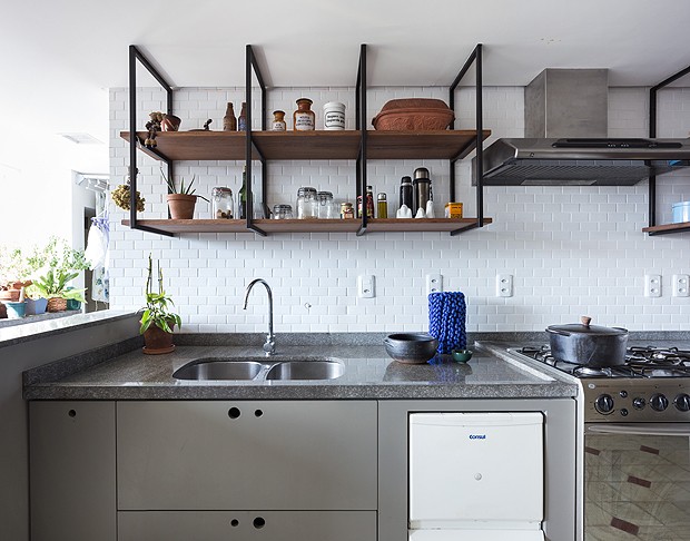 Detalhe para a parede de lajotas e para o armário totalmente aberto instalado na cozinha, que deixam o espaço com estilo despojado e industrial (Foto: Marcelo Donadussi/Fotografia de Arquitetura)