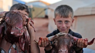 Crianças exibem cabeças de cabras decepadas, sacrificadas como parte da comemoração do feriado muçulmano de Eid al-Adha, em um acampamento para sírios deslocados pelo conflito, na vila de Killi, na província de Idlib, no noroeste dos rebeldes sírios  — Foto: AAREF WATAD / AFP