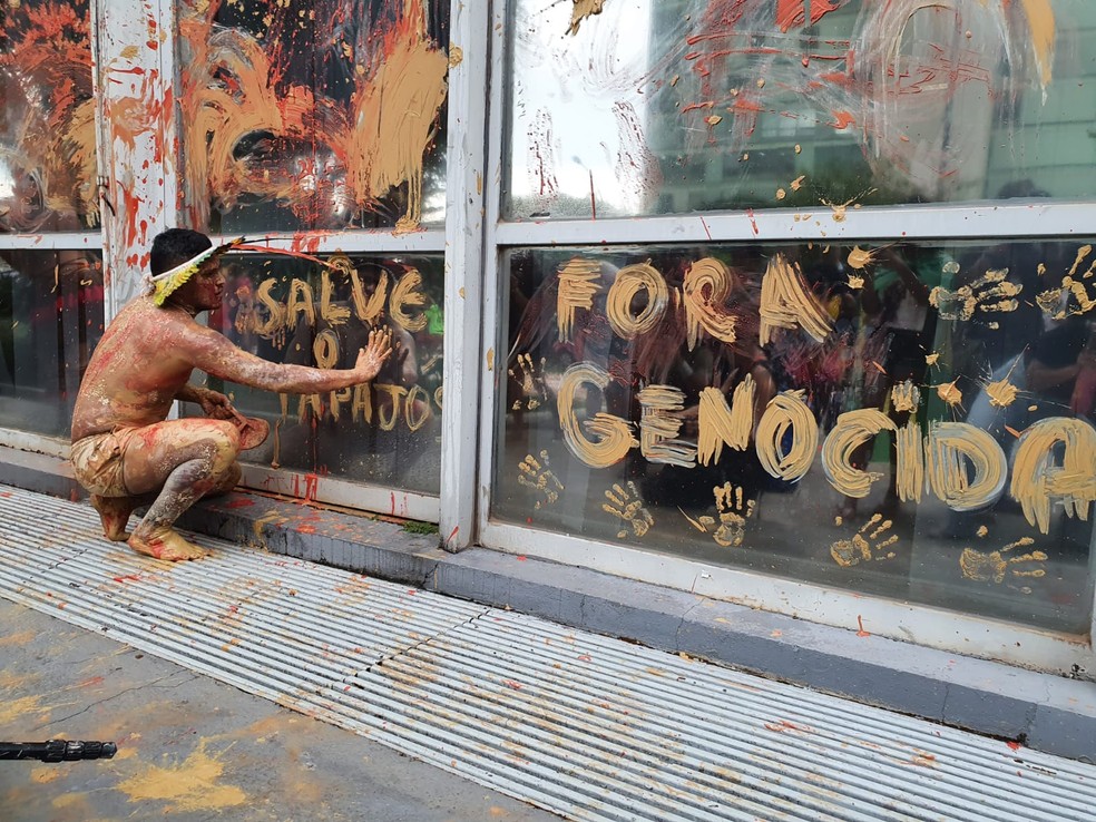 Indígena escreve, com lama, nos vidros do Ministério de Minas e Energia, durante protesto, em Brasília — Foto: Anna Reis/ TV Globo