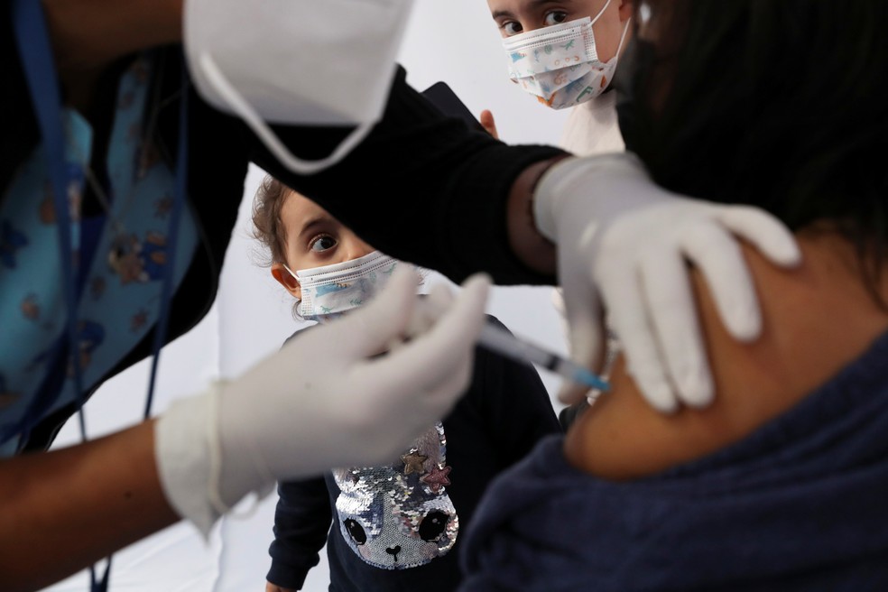 Crianças observam enquanto mulher é vacinada contra a Covid-19 em Santiago do Chile, em foto de 17 de março de 2021 — Foto: Ivan Alvarado/Reuters/Arquivo