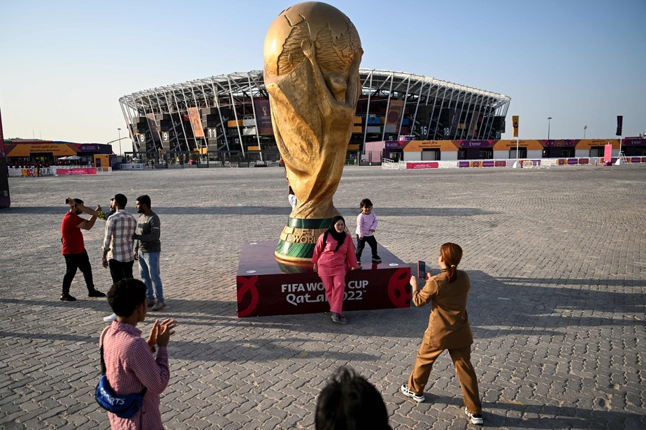Mulher tira foto em frente a réplica da taça da Copa do Mundo do Catar