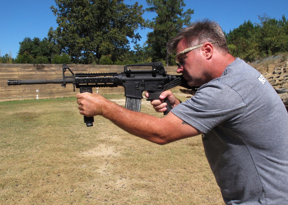 Instrutor de tiro Frankie McRae demonstra um rifle com um 