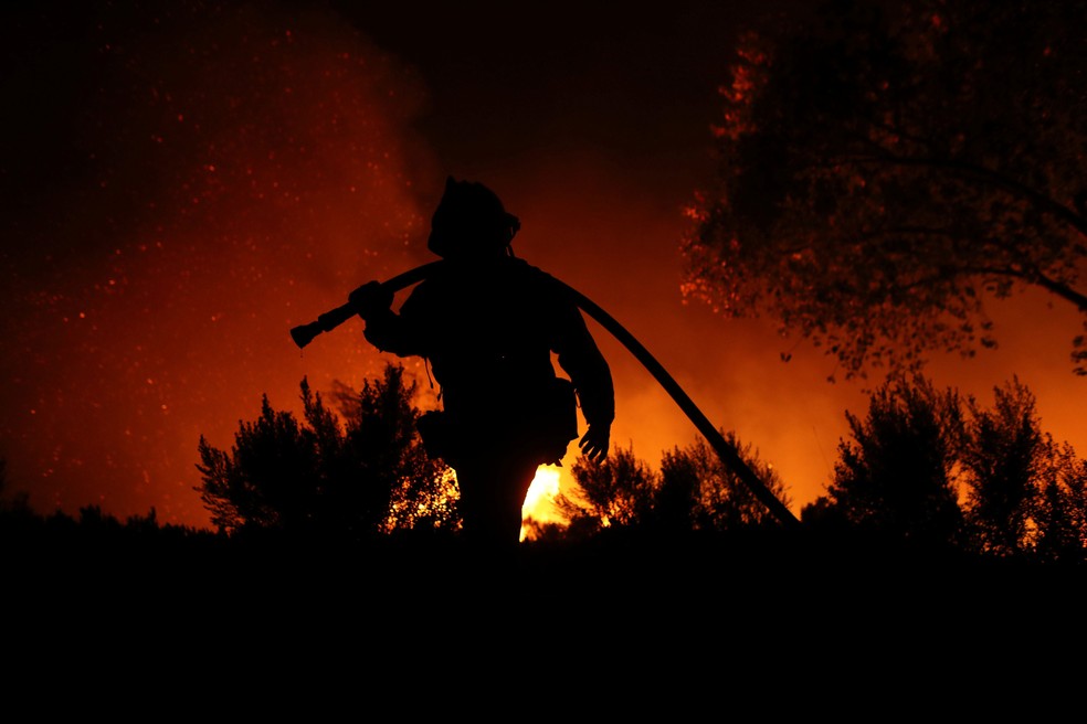Bombeiro combate incêndio em Bonsall, na California, na quinta-feira (7)  (Foto: Mike Blake/ Reuters)