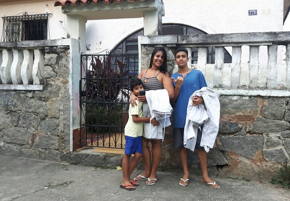 Diante da casa onde mora, Ramon segura o quimono ao lado da mãe e do irmão Anthony (Foto: Marcelo Barone)