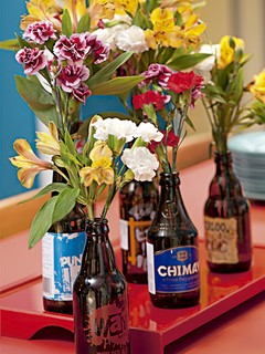 As flores ficam ainda mais simpáticas ao serem colocadas em garrafas de cervejas com rótulos diferentes