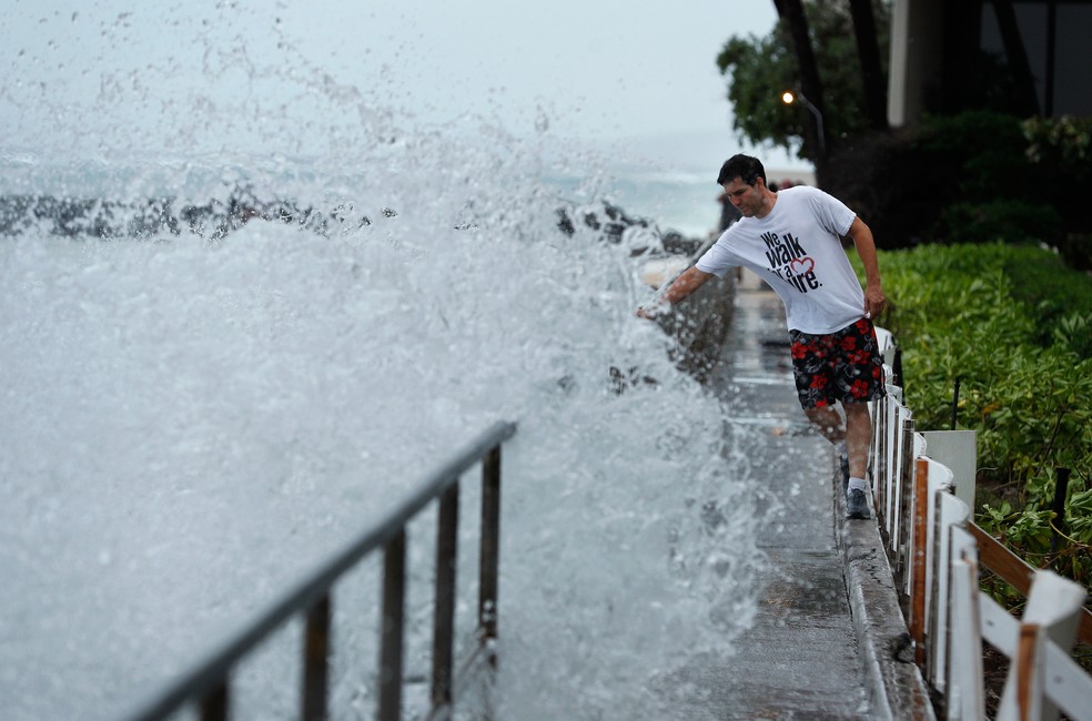 Homem evita ser atingido por uma onda em uma passarela na quinta-feira (23), em Honolulu, no HavaÃ­  (Foto: John Locher/AP)