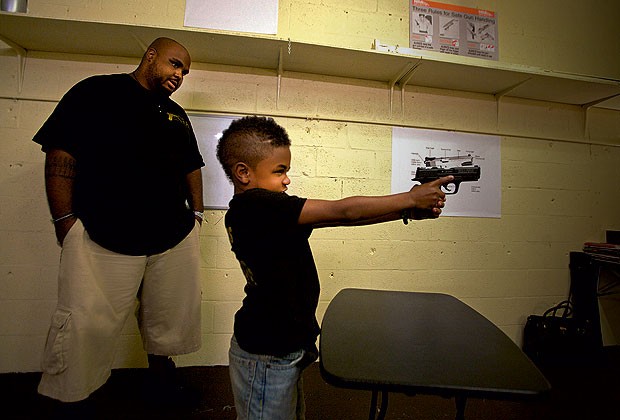 Pai e filho O instrutor de tiro Brandon observa o filho Alex (Foto: Alex Quesada)