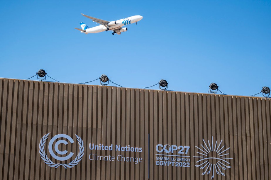 Um avião sobrevoa uma sala de conferências com o logotipo da COP27 na Cúpula do Clima da ONU