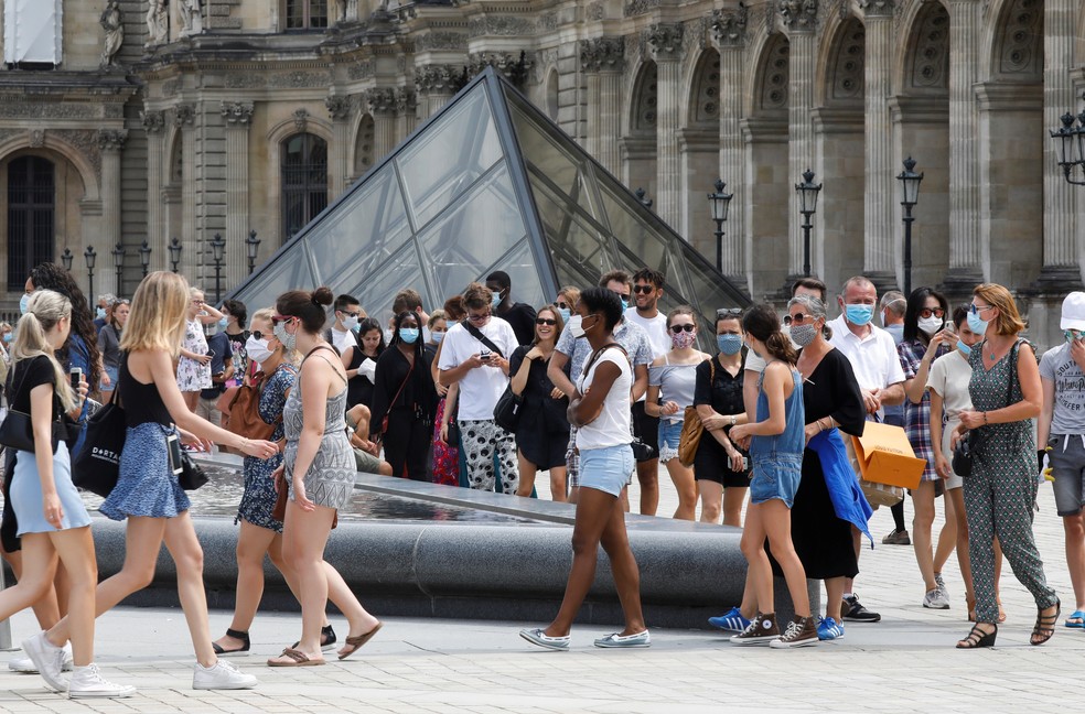 Visitantes usando máscaras protetoras fazem fila para entrar na pirâmide do Louvre em Paris, na França. — Foto: Charles Platiau/Reuters