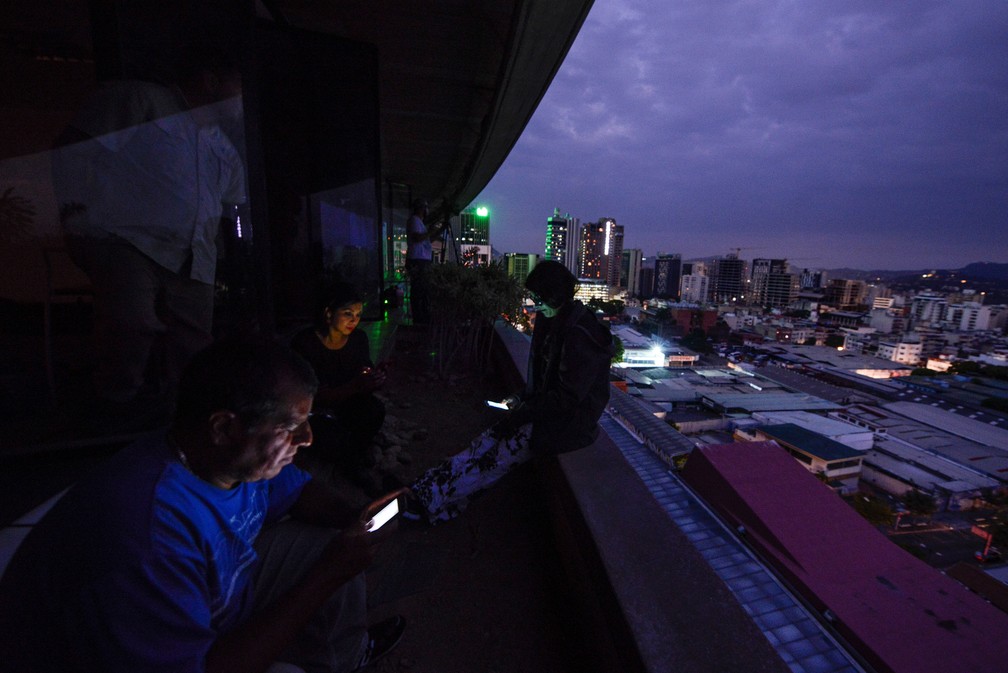 Pessoas usam celulares durante apagão em Caracas, no dia 7 de março — Foto: Matias Delacroix/AFP