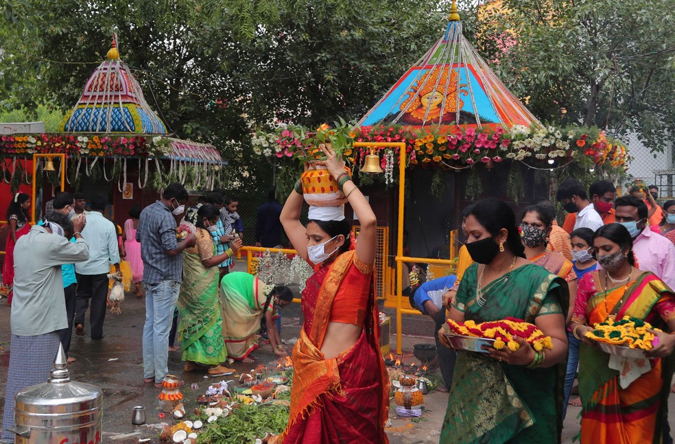 Indianos com máscaras carregam ofertas para a deusa hindu Kali durante o festival de Bonalu em Hyderabad, na Índia, neste domingo (19) — Foto:  Mahesh Kumar A./AP 