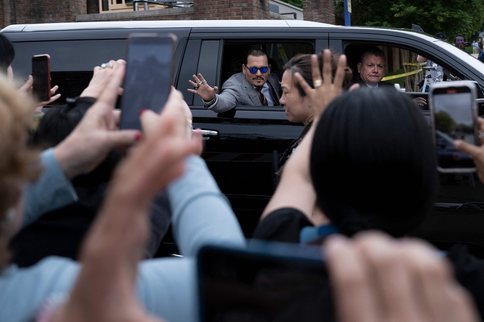 O ator Johnny Depp acena para apoiadores ao sair do Tribunal do Condado de Fairfax, Virgínia. O ator está processando a ex-esposa Amber Heard por difamação — Foto: BRENDAN SMIALOWSKI / AFP