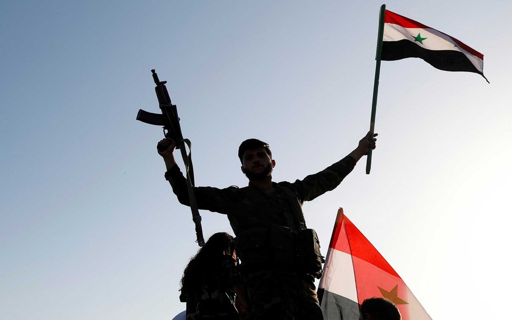 Soldado sírio armado agita bandeira contra ataques aéreos (Foto: Omar Sanadiki / Reuters)