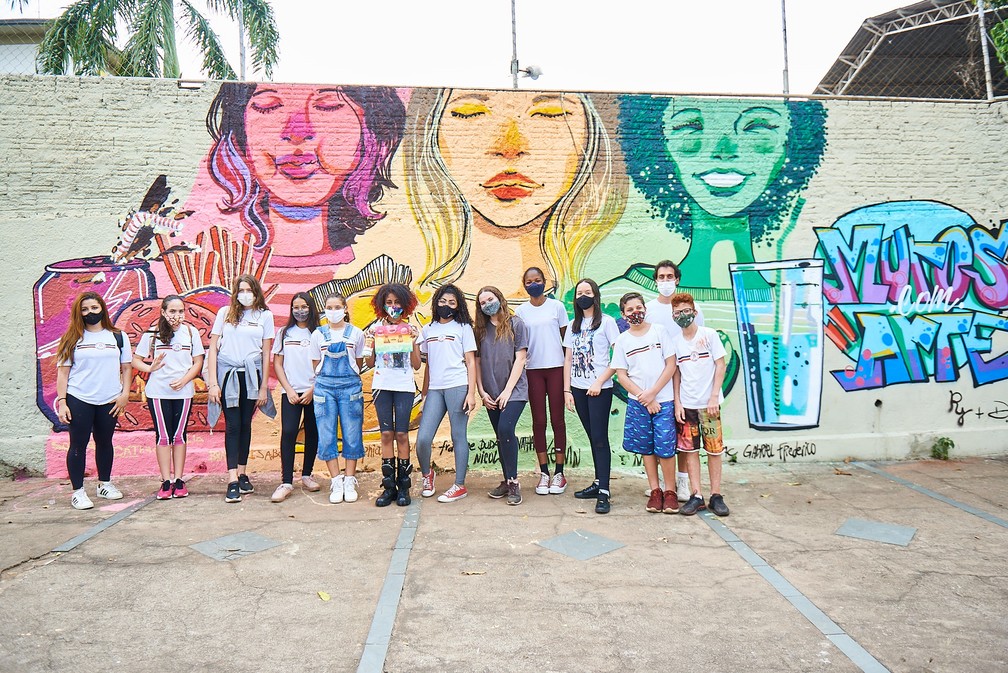 Rebeca junto de seus colegas em frente ao muro pronto do projeto 'Muros com Arte', na escola de Piracicaba — Foto: Vitor Garcia / Horizonte