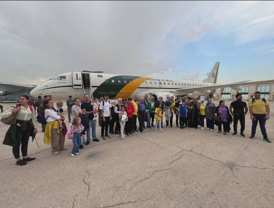 Brasileiros refugiados da Cisjordânia posam diante de avião da Força Aérea Brasileira em 1 de novembro de 2023